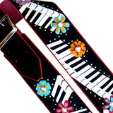 Close up of a black guitar strap featuring a Kidskin piano keyboard and flower overlays.  Centered with Swarovski Crystals.  Designer guitar strap owned by Kristin Chenoweth.