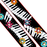 Close up of a black guitar strap featuring a Kidskin piano keyboard and flower overlays.  Centered with Swarovski Crystals.  Designer guitar strap owned by Kristin Chenoweth.